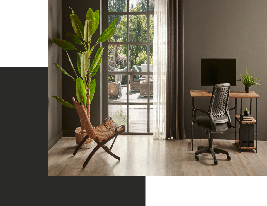 a room with a chair, desk and a plant in it.